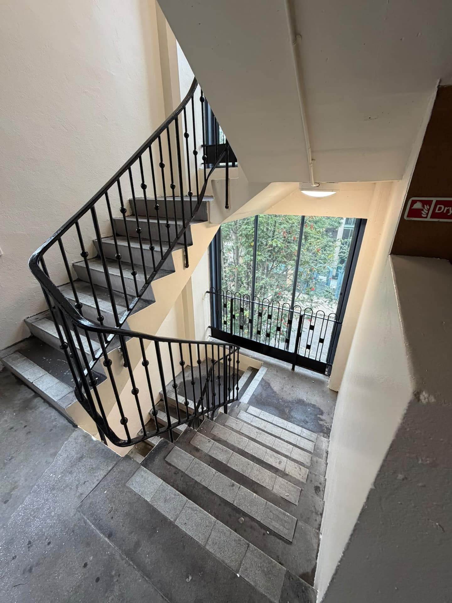 Communal stairwell in a higher-risk residential building in Camden, with cream walls, a black steel balustrade, concrete stairs and a dry riser sign