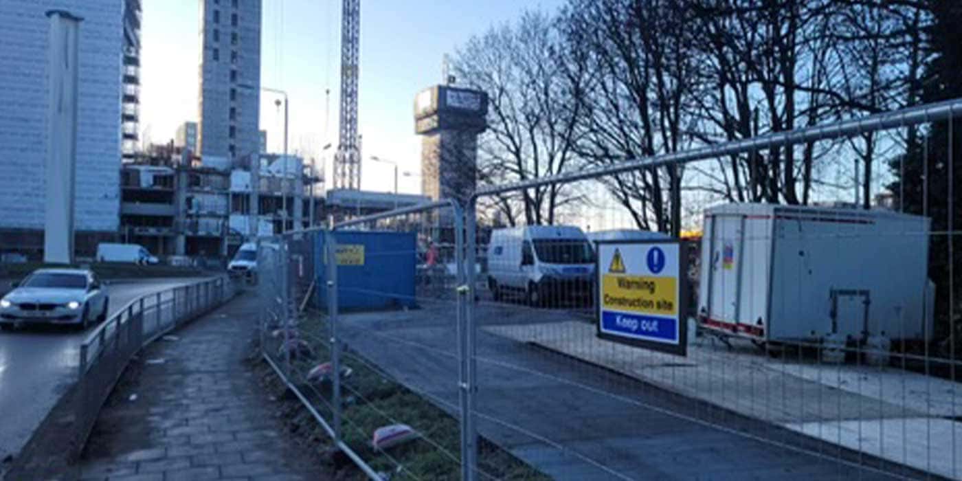 Site engineer setting out levels beside temporary fencing
