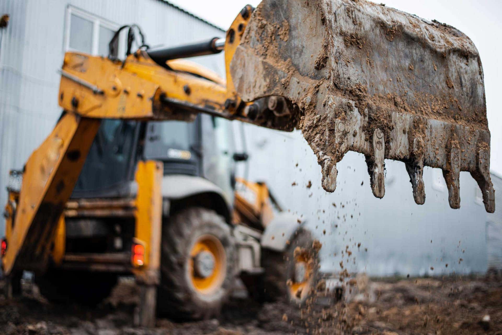 Excavator bucket lifting spoil during enabling works
