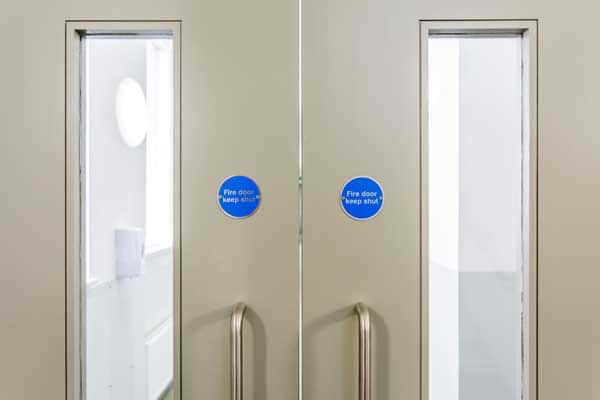Fire door keep shut sign fixed to a timber door