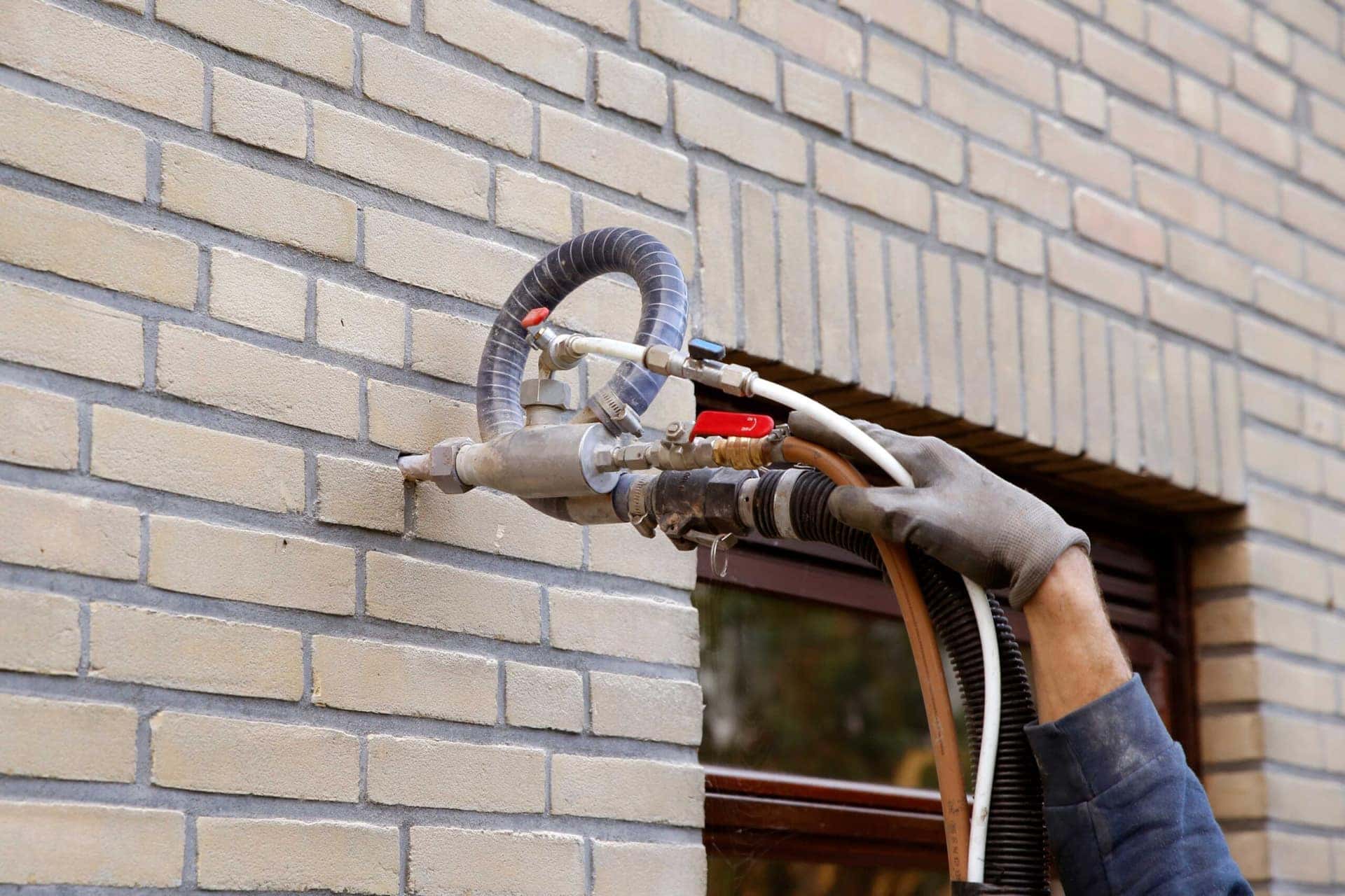 Cavity wall insulation being injected through a drilled hole